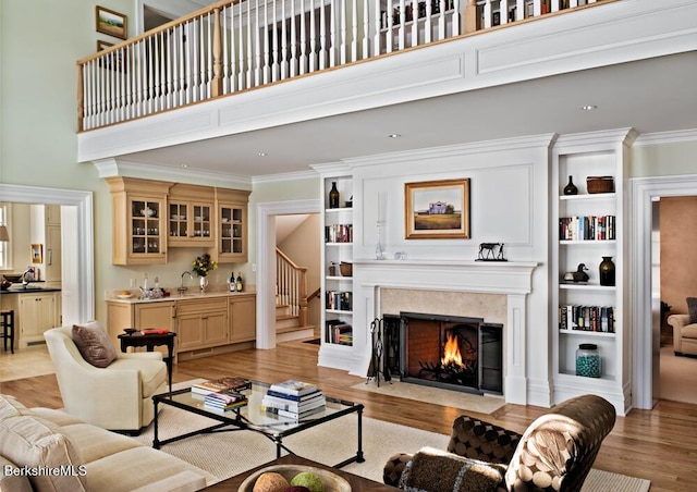 258 Sandisfield Rd, New Marlborough, MA 01230 - living room featuring light wood-style flooring, crown molding, a premium fireplace, a high ceiling, and stairs