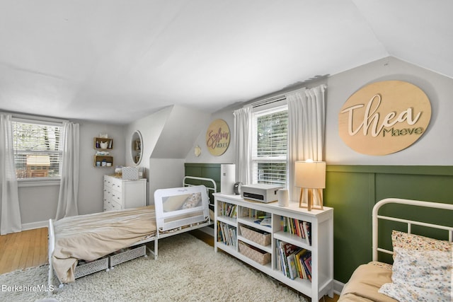bedroom featuring lofted ceiling, wood finished floors, and multiple windows