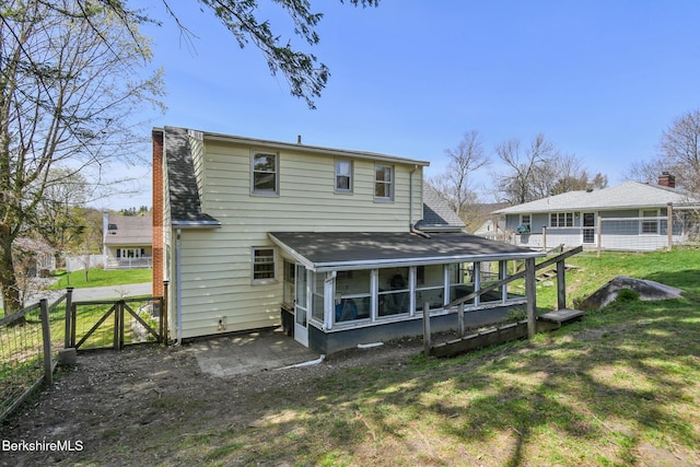 back of property featuring roof with shingles, fence, a sunroom, a chimney, and a yard