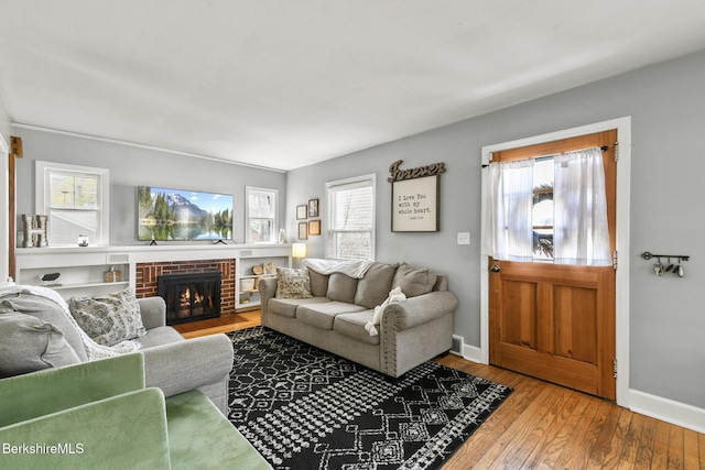 living area featuring a healthy amount of sunlight, baseboards, a fireplace, and hardwood / wood-style floors