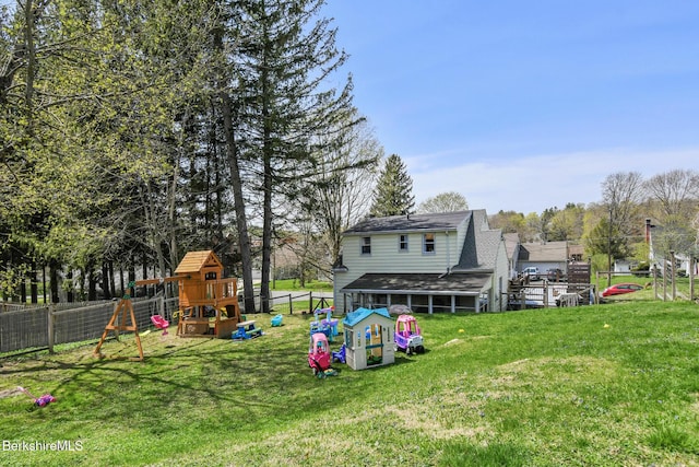 exterior space with a lawn, a fenced backyard, a playground, and roof with shingles