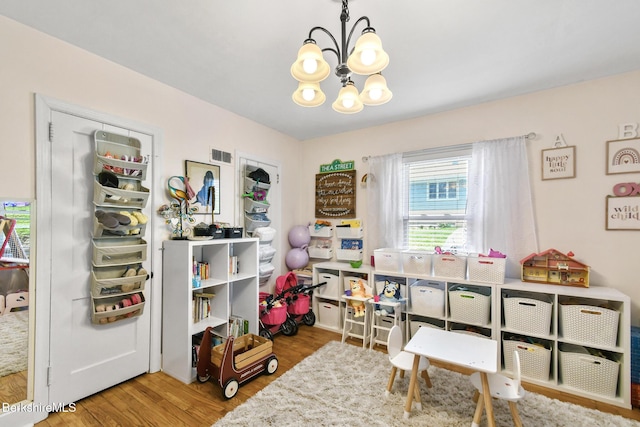 rec room with a notable chandelier, wood finished floors, and visible vents
