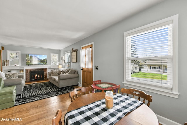dining area featuring baseboards, a fireplace, and wood finished floors