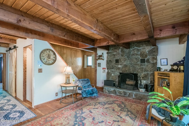 78 Slope Rd, Tolland, MA 01034 - living room featuring wood ceiling with exposed beams, wood finished floors, a barn door, a stone fireplace, and baseboards