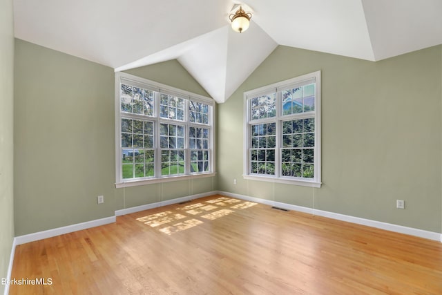 unfurnished room featuring light wood-type flooring, lofted ceiling, visible vents, and baseboards