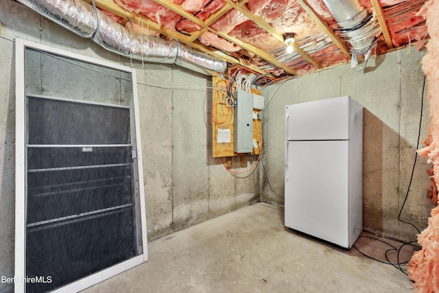 unfinished basement featuring freestanding refrigerator and electric panel