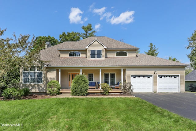 traditional-style home featuring driveway, covered porch, a garage, and a front lawn