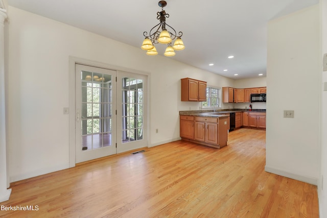 kitchen featuring pendant lighting, brown cabinets, dark countertops, visible vents, and light wood-type flooring