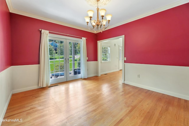 spare room featuring light wood finished floors, visible vents, crown molding, french doors, and a chandelier