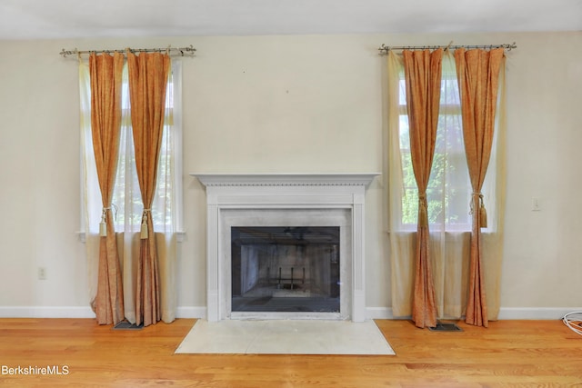 interior details with a fireplace with flush hearth, baseboards, and wood finished floors