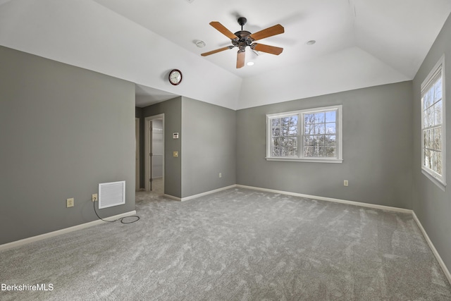 spare room featuring carpet floors, baseboards, visible vents, and vaulted ceiling