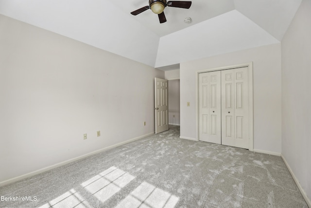 unfurnished bedroom featuring lofted ceiling, ceiling fan, light carpet, baseboards, and a closet