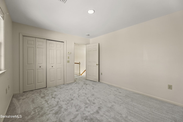 unfurnished bedroom with baseboards, a closet, and light colored carpet