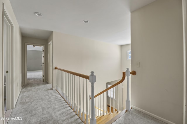 corridor with recessed lighting, baseboards, light colored carpet, and an upstairs landing