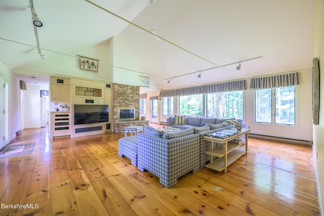 33 Interlaken Rd, Stockbridge, MA 01262 - living room with track lighting, a baseboard radiator, hardwood / wood-style floors, a stone fireplace, and vaulted ceiling