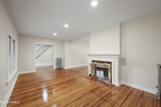 32 Hampshire St, Pittsfield, MA 01201 - unfurnished living room featuring radiator heating unit, stairway, wood-type flooring, a fireplace, and recessed lighting