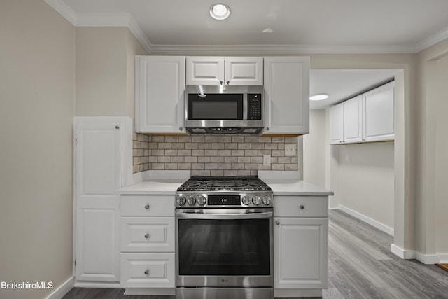 32 Hampshire St, Pittsfield, MA 01201 - kitchen featuring stainless steel appliances, decorative backsplash, light countertops, light wood finished floors, and ornamental molding
