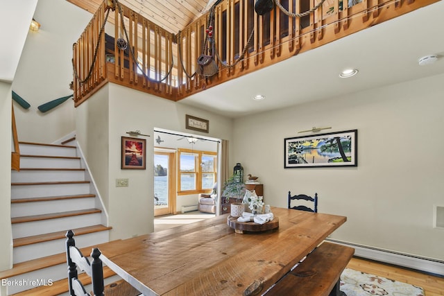 dining area with a baseboard radiator, stairway, a high ceiling, and wood finished floors
