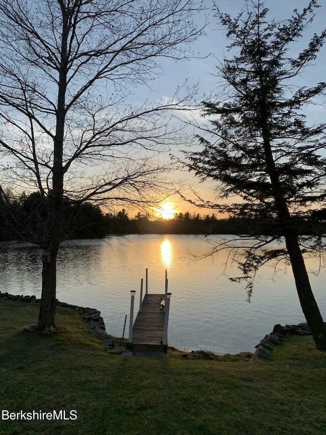 view of dock with a lawn and a water view
