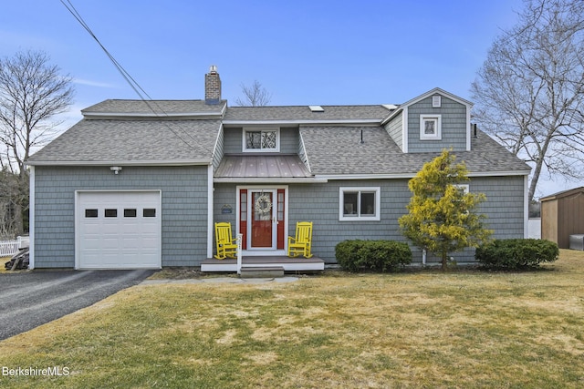view of front of house featuring a chimney, a garage, a front yard, driveway, and a shingled roof