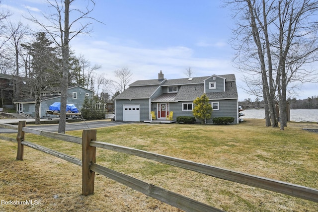 colonial inspired home with fence, driveway, a shingled roof, and a garage