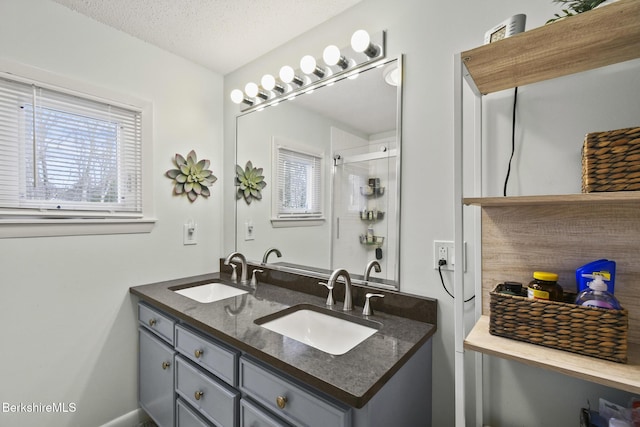 bathroom featuring a sink, plenty of natural light, a textured ceiling, and a shower stall