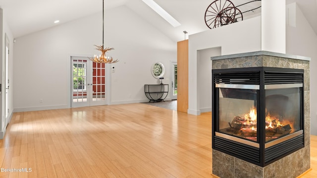 2017 Monterey Rd, Otis, MA 01253 - living area with a multi sided fireplace, high vaulted ceiling, a skylight, light wood finished floors, and a chandelier