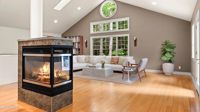 2017 Monterey Rd, Otis, MA 01253 - living area featuring a multi sided fireplace, wood finished floors, high vaulted ceiling, a skylight, and recessed lighting