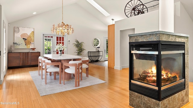 2017 Monterey Rd, Otis, MA 01253 - dining space featuring a multi sided fireplace, high vaulted ceiling, light wood-style floors, a skylight, and a chandelier