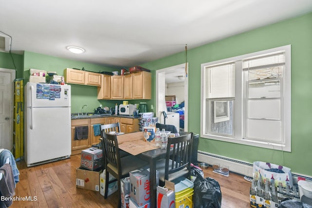 kitchen with a baseboard radiator, a sink, hardwood / wood-style floors, and white appliances