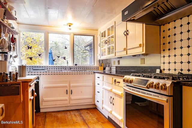 kitchen featuring white cabinets, custom exhaust hood, high end range, and light hardwood / wood-style flooring