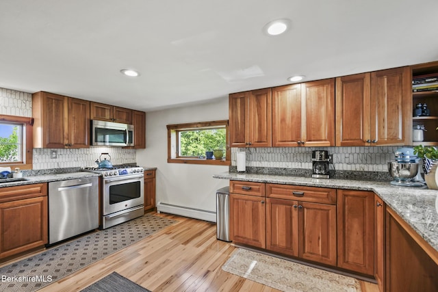 288 Johnson Rd, Dalton, MA 01226 - kitchen featuring appliances with stainless steel finishes, a baseboard radiator, decorative backsplash, light wood finished floors, and brown cabinets