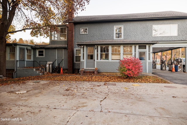 back of house with a carport, aphalt driveway, and entry steps