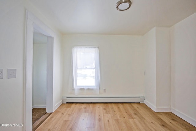 empty room with baseboard heating and light wood-type flooring