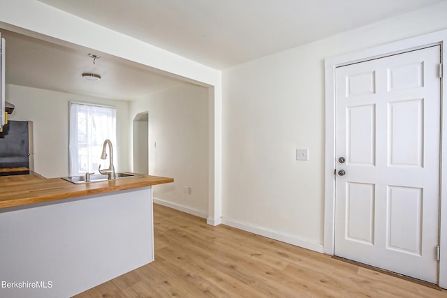 kitchen with wood counters, stainless steel fridge, light hardwood / wood-style flooring, and sink