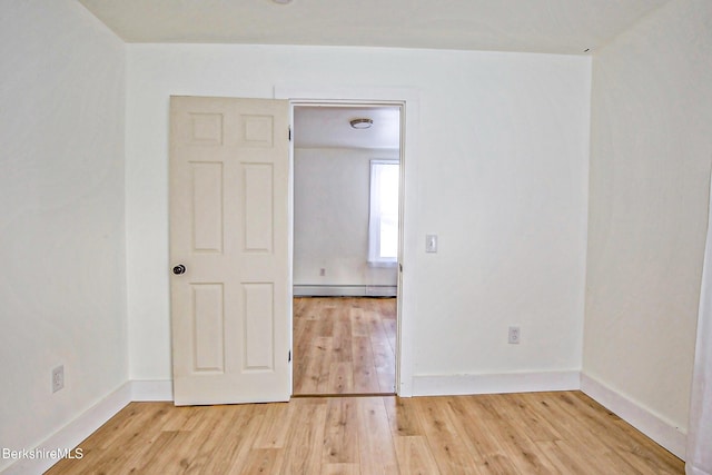 spare room with hardwood / wood-style flooring and a baseboard heating unit