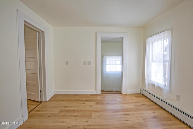 unfurnished room featuring light wood-type flooring and baseboard heating