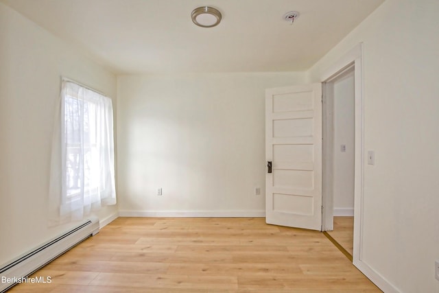 spare room with baseboard heating, a wealth of natural light, and light hardwood / wood-style floors