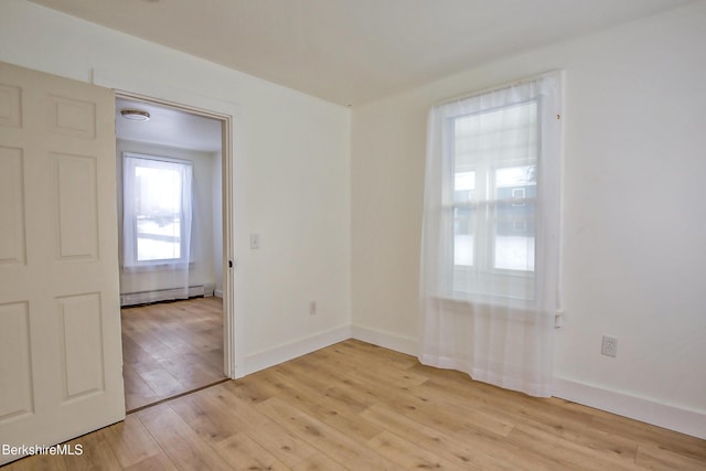 spare room featuring light wood-type flooring and baseboard heating