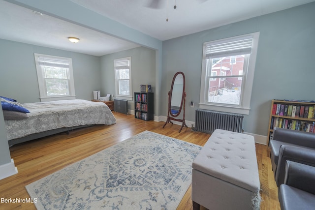 bedroom featuring radiator heating unit, light hardwood / wood-style flooring, and ceiling fan