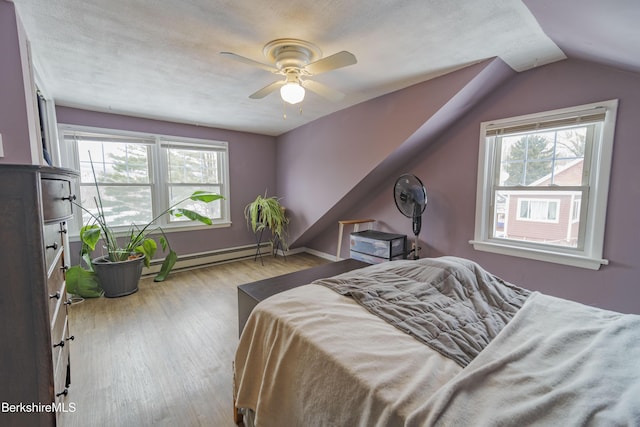 bedroom with multiple windows, ceiling fan, light wood-type flooring, and a baseboard heating unit