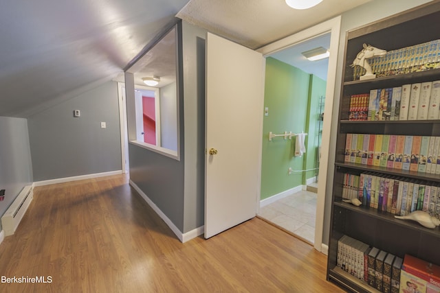 corridor featuring baseboard heating, hardwood / wood-style floors, and vaulted ceiling