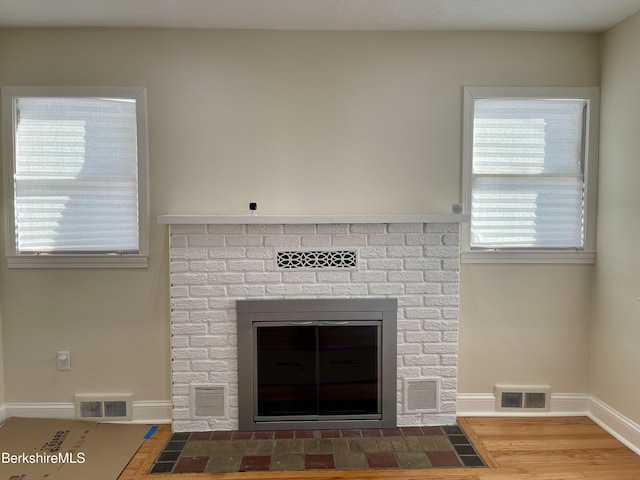 interior details featuring a brick fireplace and wood-type flooring