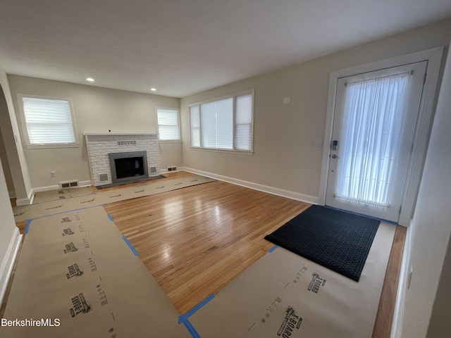 entrance foyer featuring a brick fireplace and hardwood / wood-style flooring