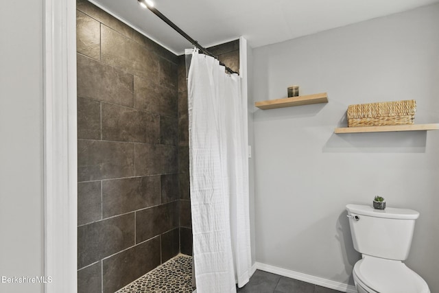 bathroom featuring tiled shower, toilet, tile patterned flooring, and baseboards