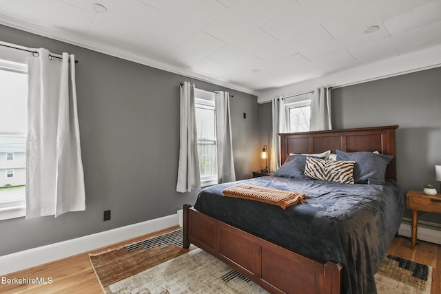 bedroom featuring wood finished floors, a baseboard radiator, and baseboards