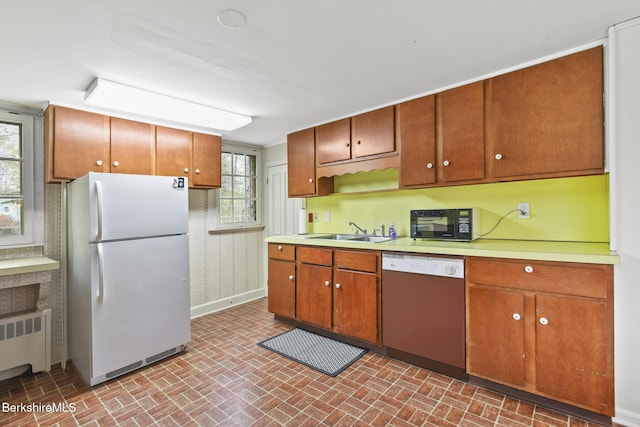 kitchen with freestanding refrigerator, dishwashing machine, radiator, black microwave, and a sink