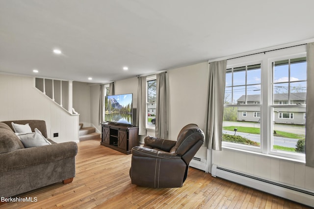 living room featuring baseboard heating, light wood-style flooring, stairway, healthy amount of natural light, and recessed lighting