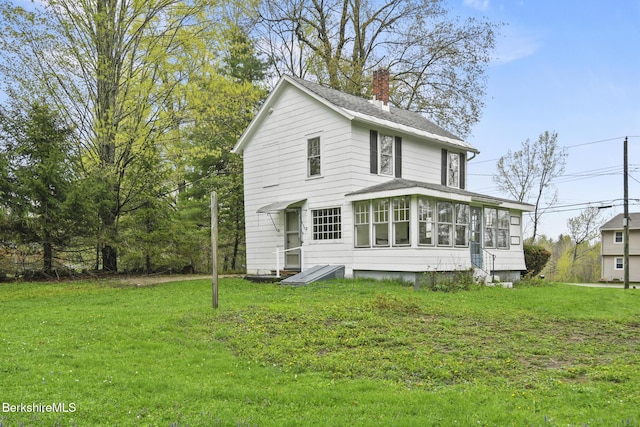 view of front of house featuring a sunroom, a chimney, and a front yard