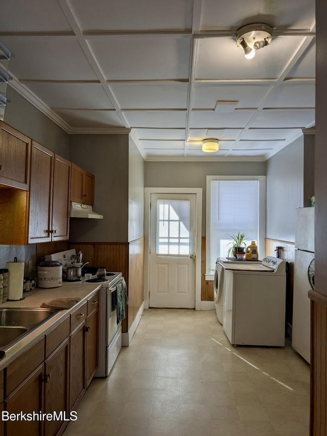 kitchen with coffered ceiling, wood walls, crown molding, white appliances, and independent washer and dryer